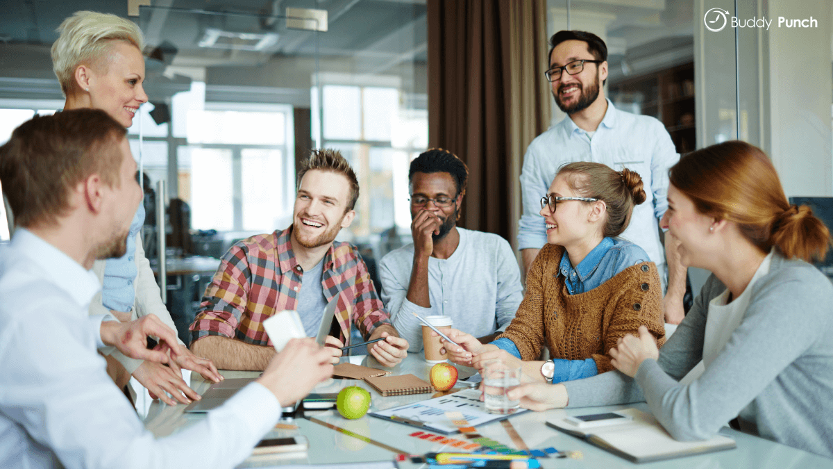 Group of employees sitting around a table smiling and happy.