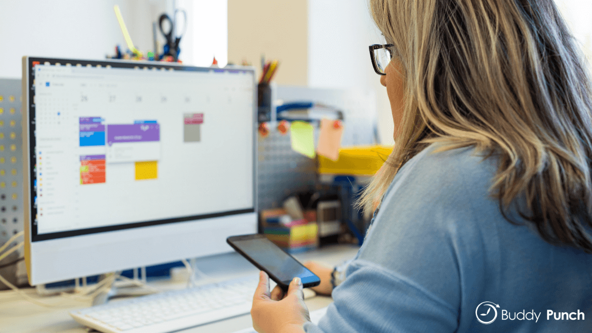 Woman sitting at computer using scheduling software to help her create employee schedules.