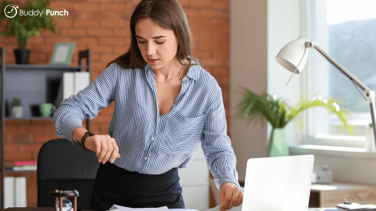 Woman looking at her watch to ensure she's on task. Alternatively, she can use employee time clock software to help manage her time. 