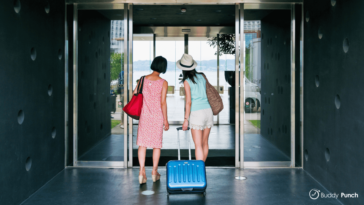 Two guests walking into a hotel during busy months of the year.