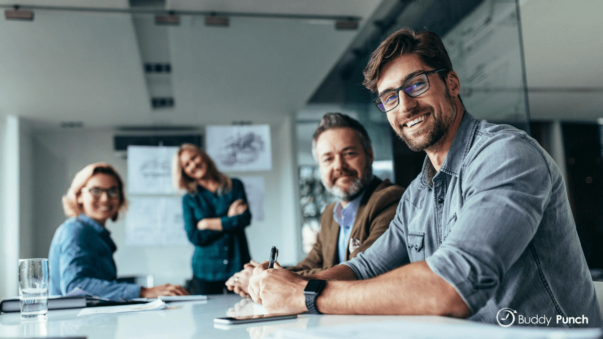 Employees sitting at a table happy because they are using a great time clock solution.