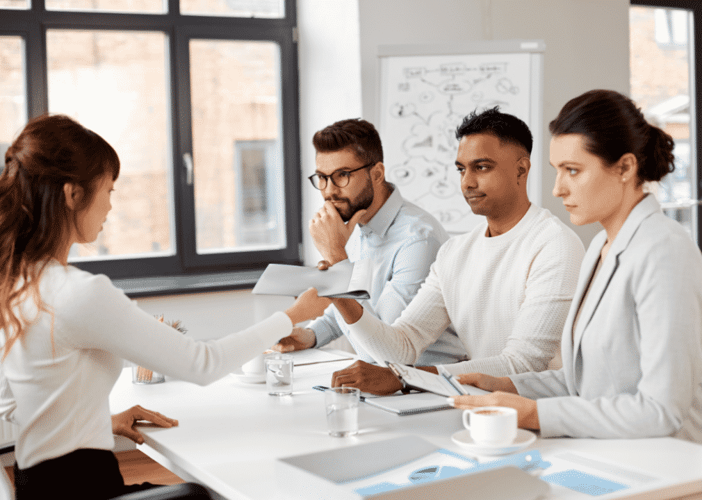 Four coworkers sit around a desk.